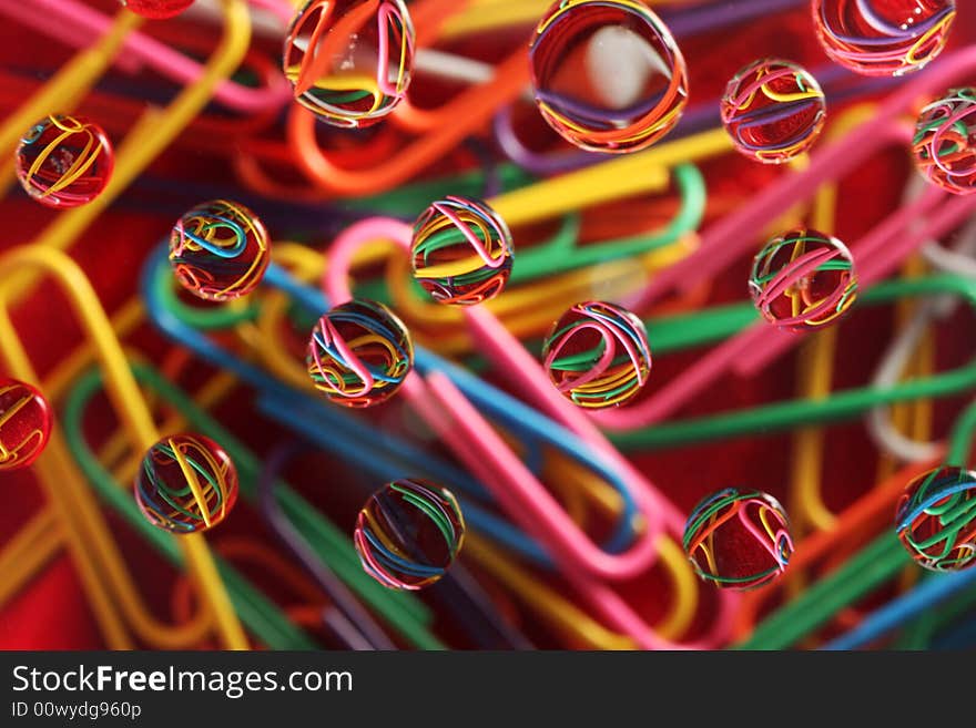 Water drops on top of colorful paperclips, focus on reflection in drops, great for backgrounds and designs. Water drops on top of colorful paperclips, focus on reflection in drops, great for backgrounds and designs