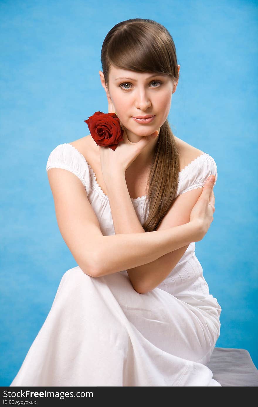 Attractive brunette with red rose isolated on blue