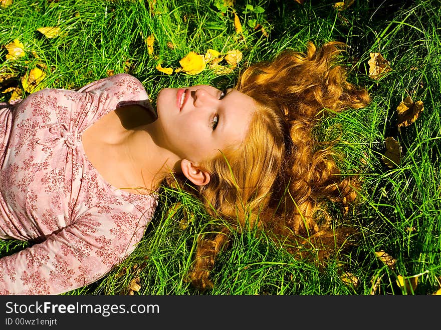 Looking to camera beauty girl with big breast is smiling and relaxing on the grass. Looking to camera beauty girl with big breast is smiling and relaxing on the grass