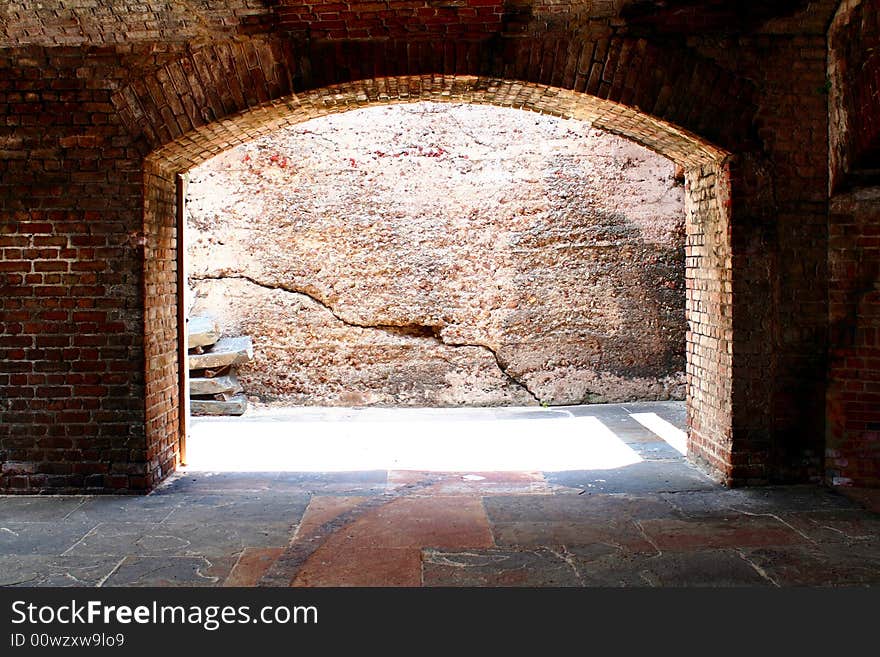 A brick arch way with daylight shinny through.