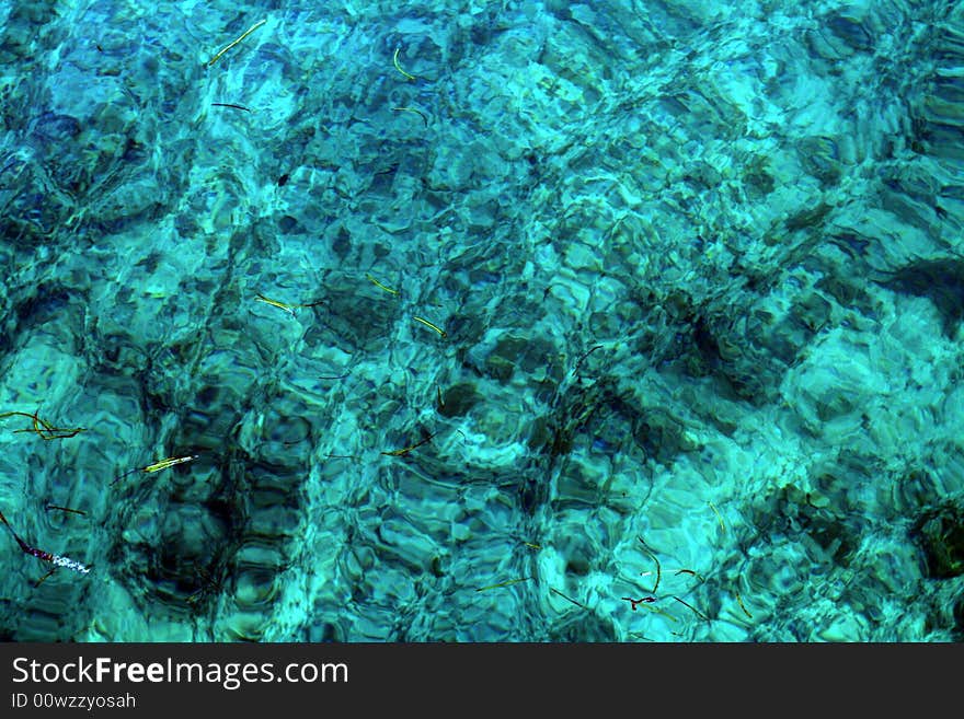 Very textured and wavy blue liquid with grass floating on the surface/