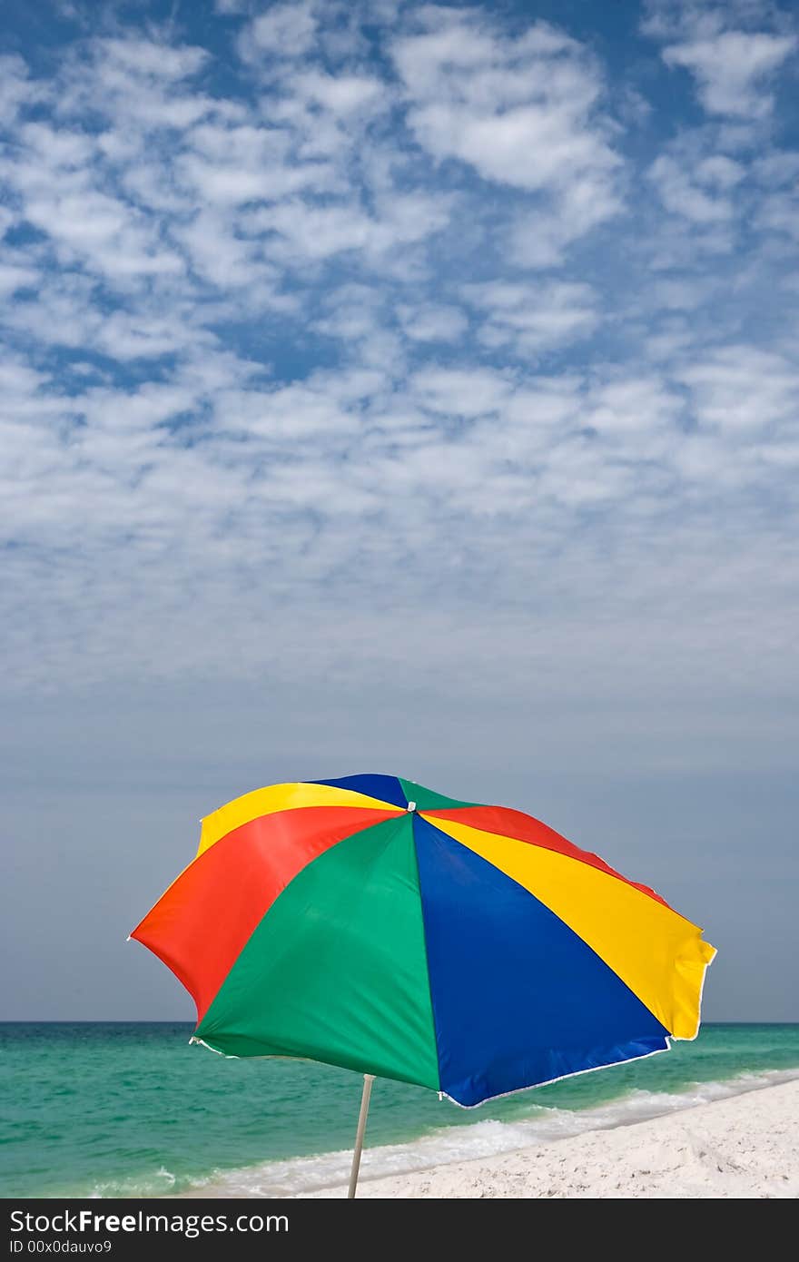 Bright beach umbrella on clean empty beach with emerald seacoast. Good background photo. Bright beach umbrella on clean empty beach with emerald seacoast. Good background photo