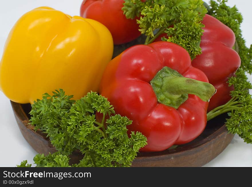 Red and yellow pepper with greens in a basket on a white background. Red and yellow pepper with greens in a basket on a white background.