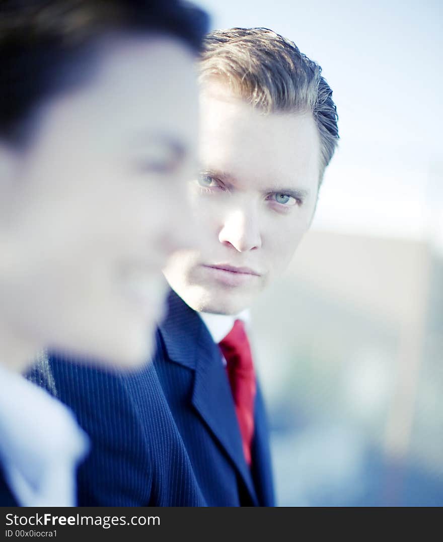 Handsome businessman looking at camera while businesswoman looks forward. Handsome businessman looking at camera while businesswoman looks forward