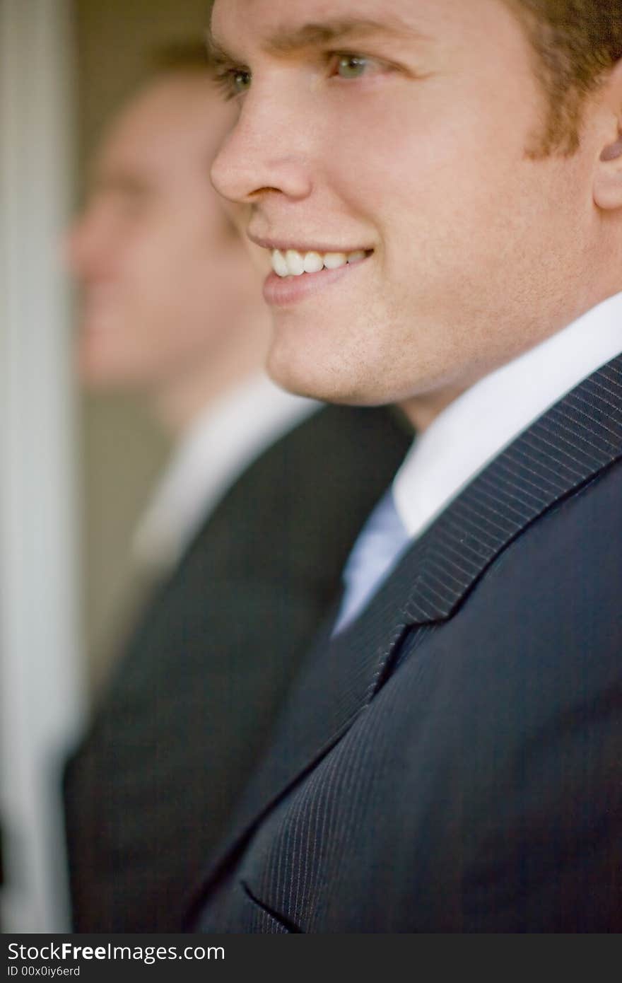 Close up of two businessmen wearing suits smiling in profile view