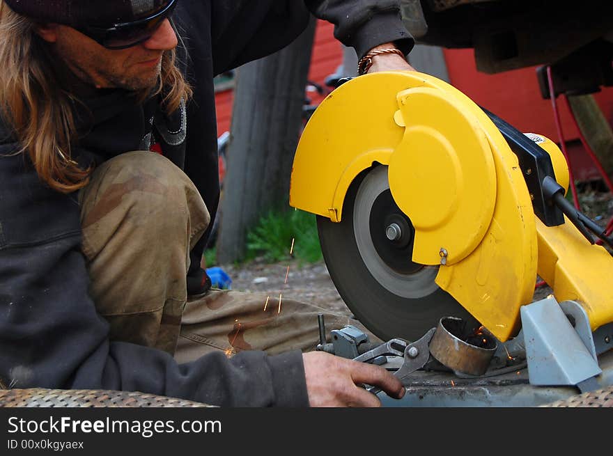 A man operating a cut-off saw to cut a pipe.