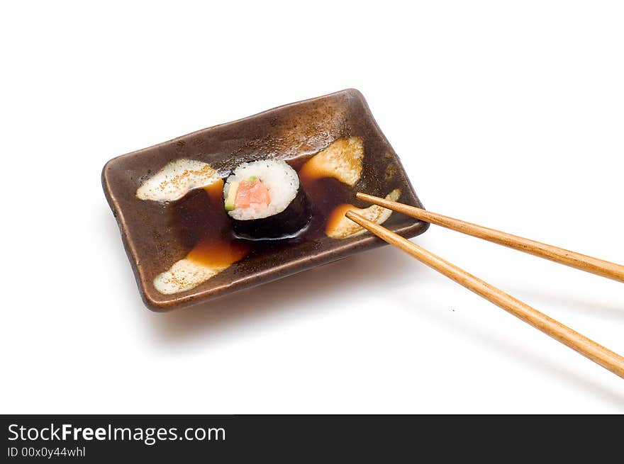 Salmon roll with avocado in soy with chopsticks