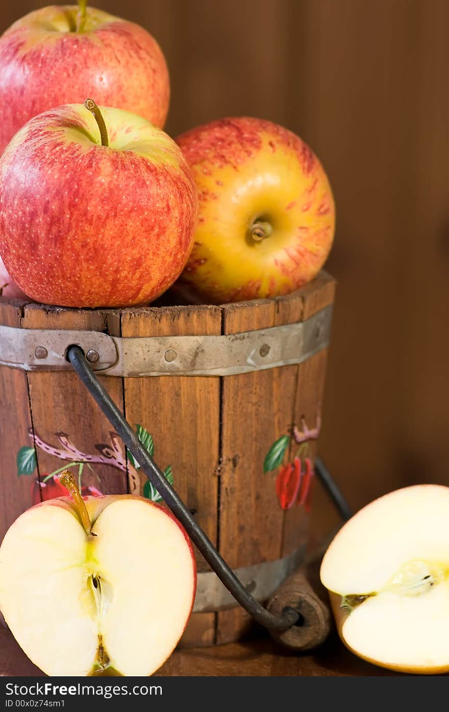 Fresh apples in bucket and on plate against wooden background