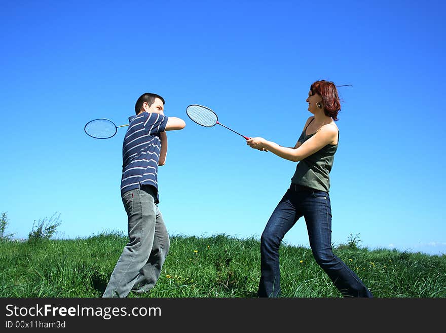 Young couple playing badminton outdoor. Young couple playing badminton outdoor