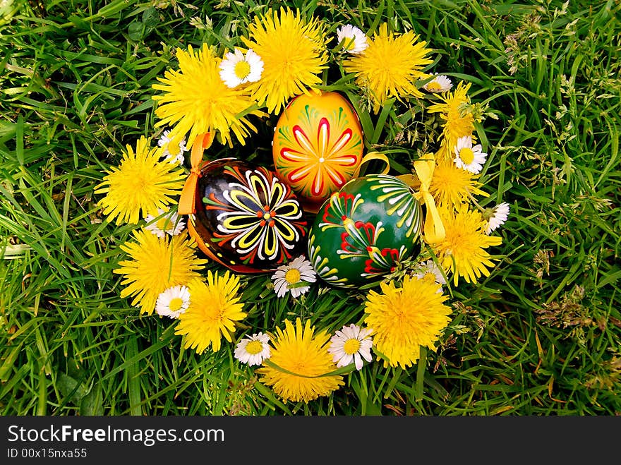 Easter eggs and dandelions chain on grass