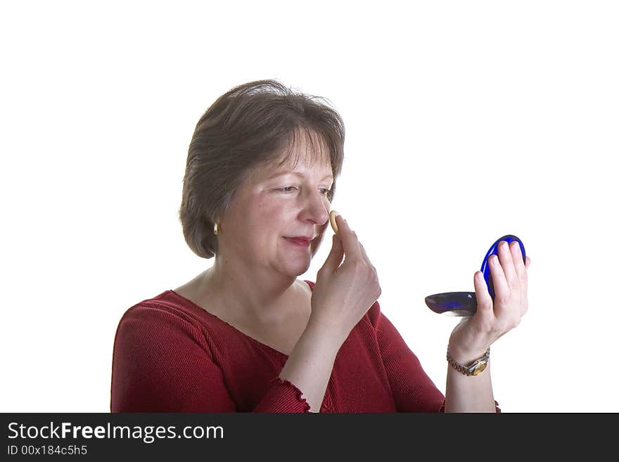 An attractive middle aged woman applying makeup. An attractive middle aged woman applying makeup