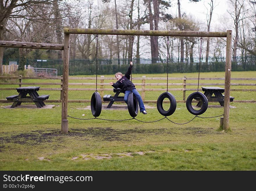 Girl playing on tyre swings in the park. Girl playing on tyre swings in the park