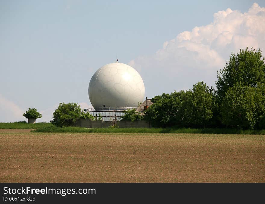 A landscape with an army radar and a field in the front