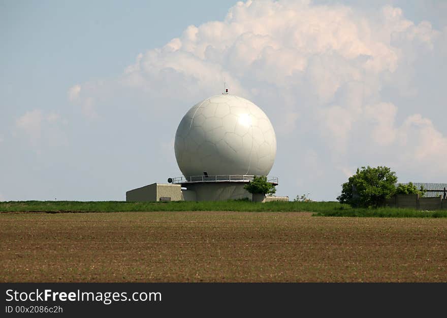 A landscape with an army radar and a field in the front