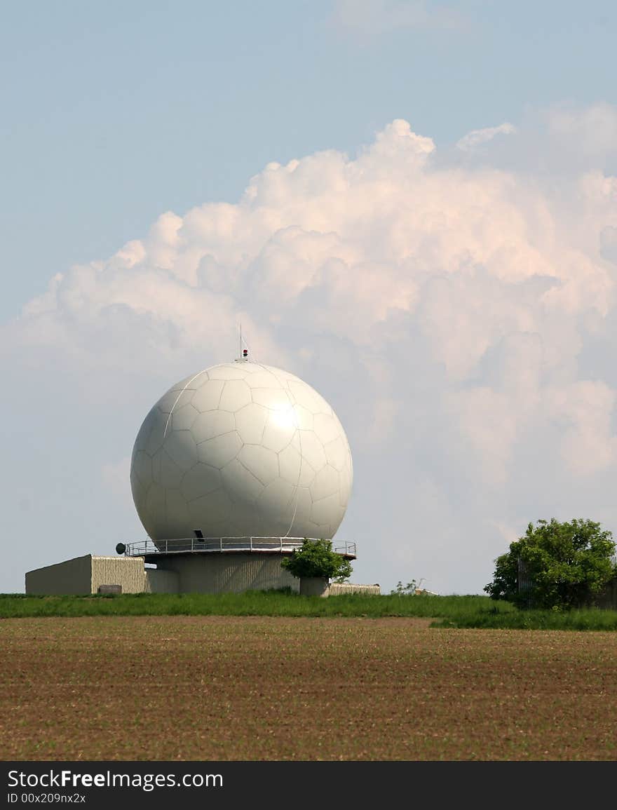 A landscape with an army radar and a field in the front