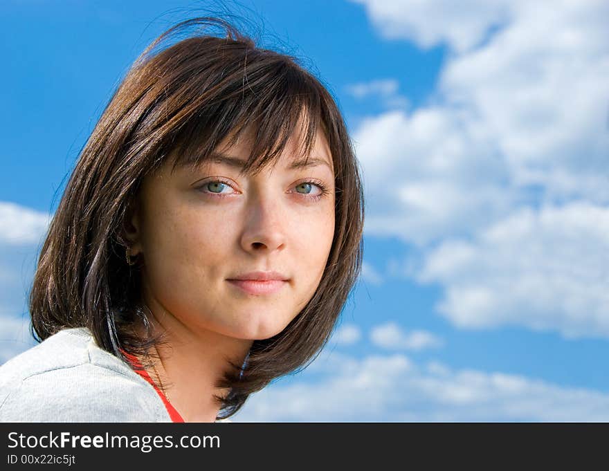 Cute brunette portrait on the sky background.