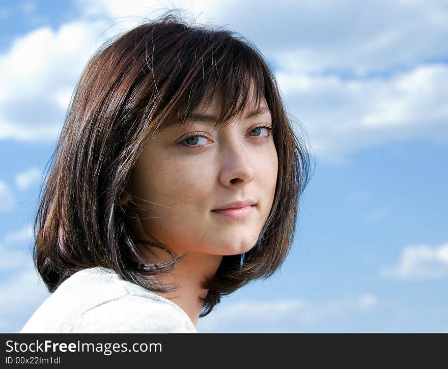 Cute brunette portrait on the sky background.