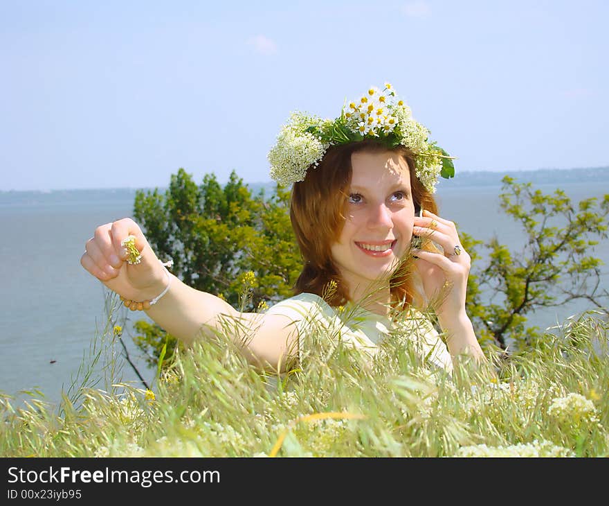 A smiling girl with a chaplet on a head speaks on a mobile telephone. A smiling girl with a chaplet on a head speaks on a mobile telephone.