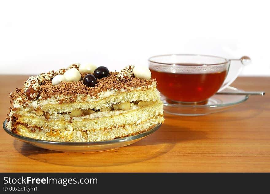 Cup of tea, spoon and cake isolated on white background