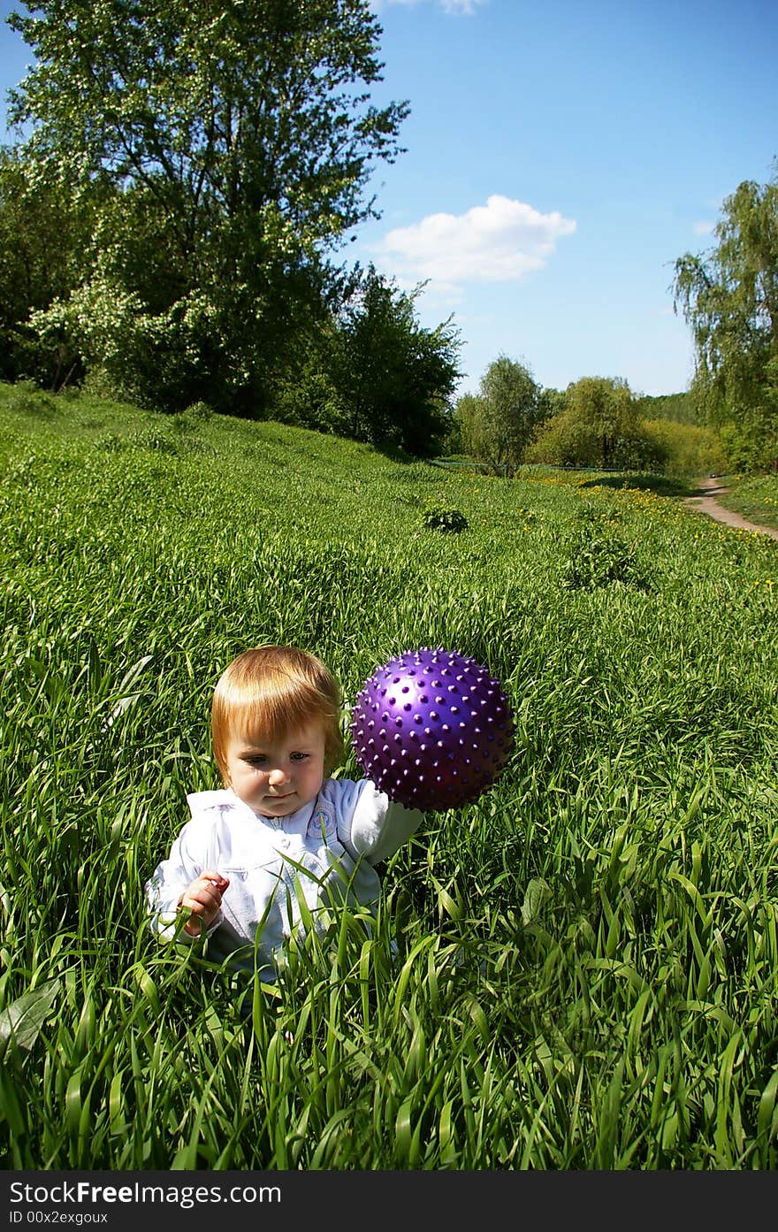 Girl sits on a grass with a ball