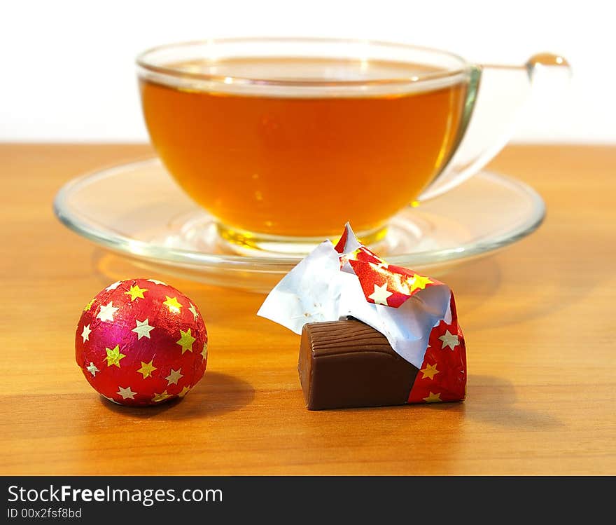 Chocolates in a red wrapper and a cup of tea. Chocolates in a red wrapper and a cup of tea