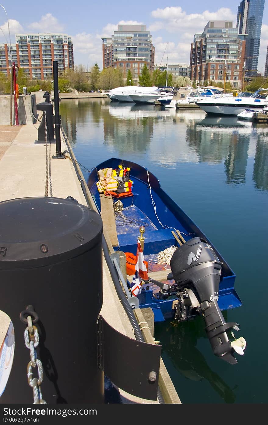 A small aluminum boat with a marine engine at the lakeshore on a sunny day. A small aluminum boat with a marine engine at the lakeshore on a sunny day