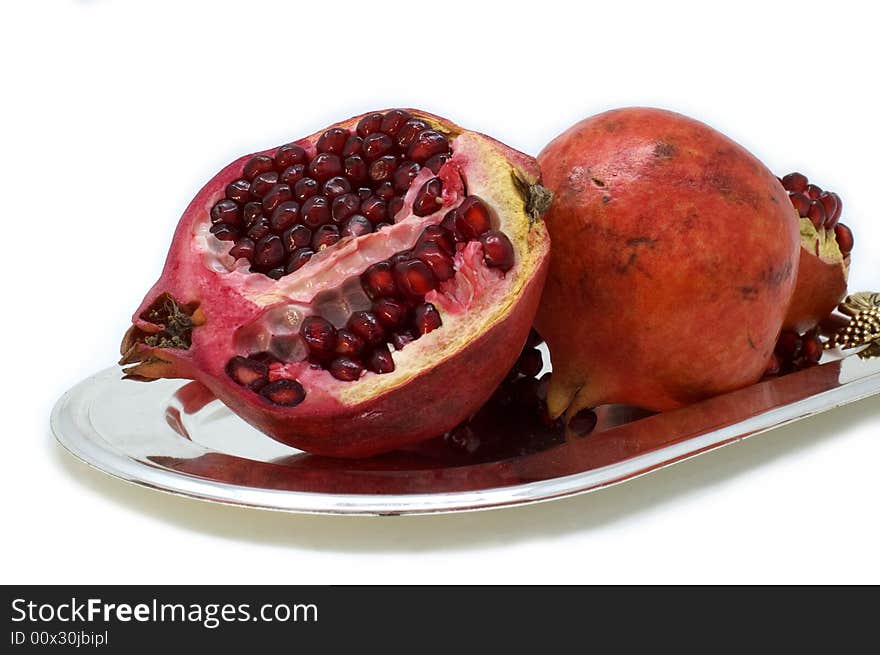 Ripe red pomegranate in a plate on a white background. Ripe red pomegranate in a plate on a white background.