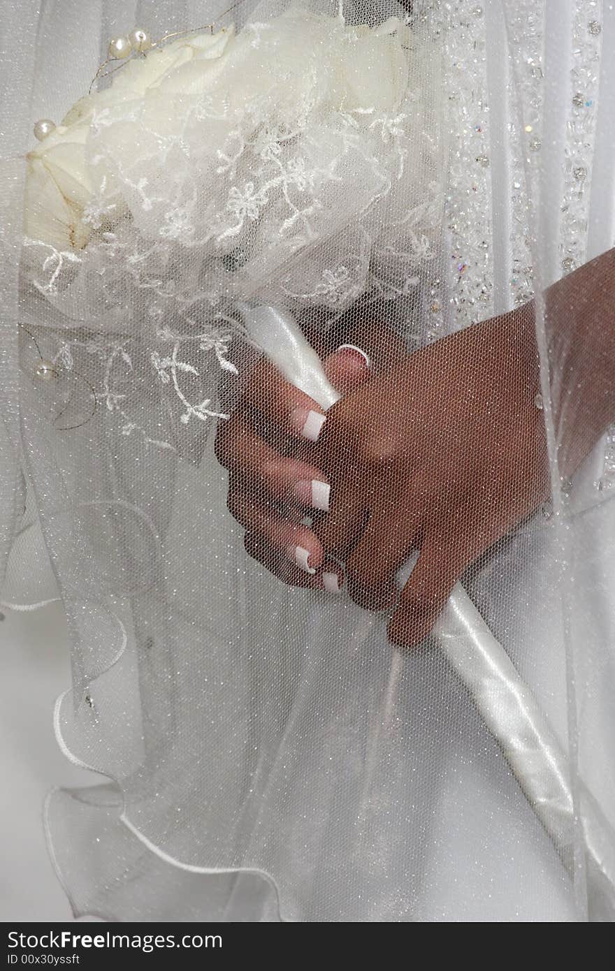 A bride holding her bouquet under her veil. A bride holding her bouquet under her veil