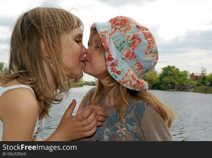 Two lovely kissing girls on the bank of river. Two lovely kissing girls on the bank of river