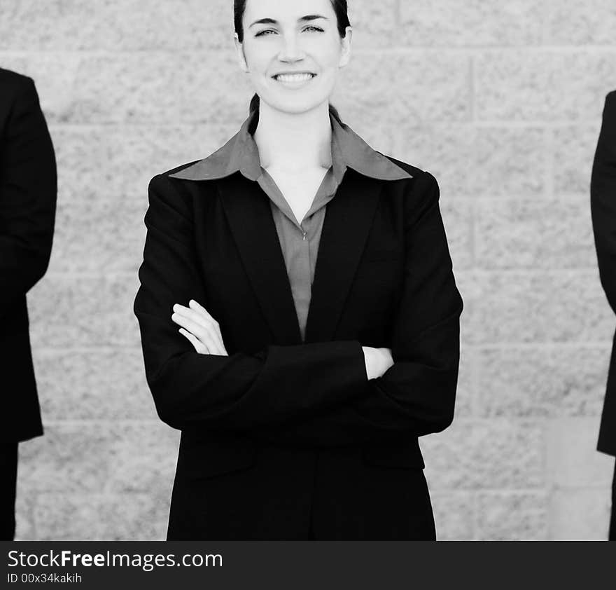 Attractive businesswoman stands between two businessmen in suits. Attractive businesswoman stands between two businessmen in suits