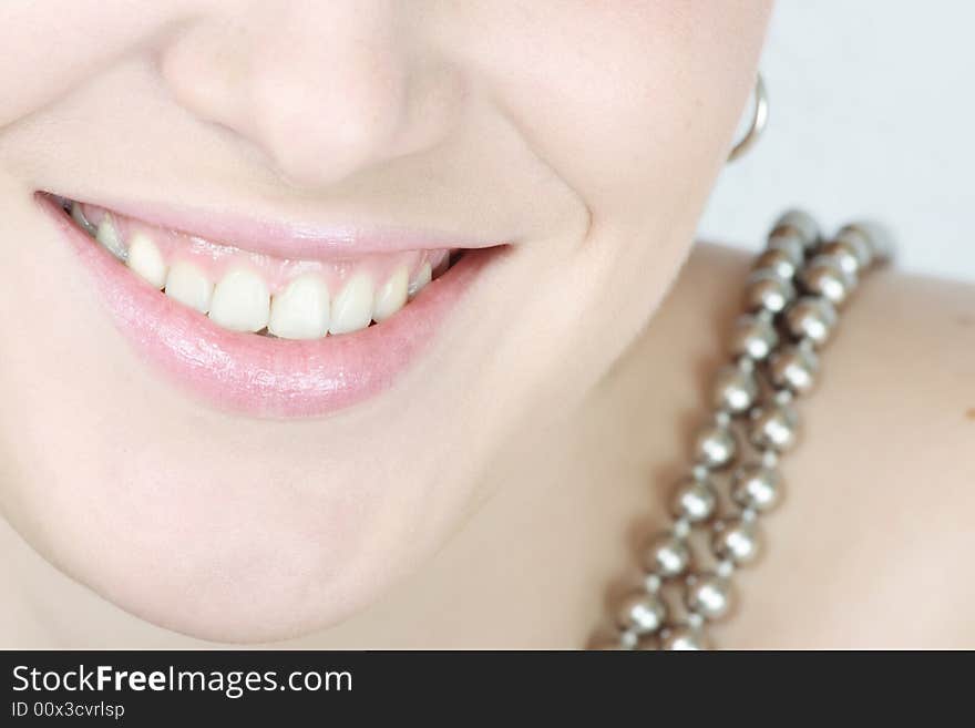 Close up of lips and teeth of a smiling woman with a necklace. Close up of lips and teeth of a smiling woman with a necklace