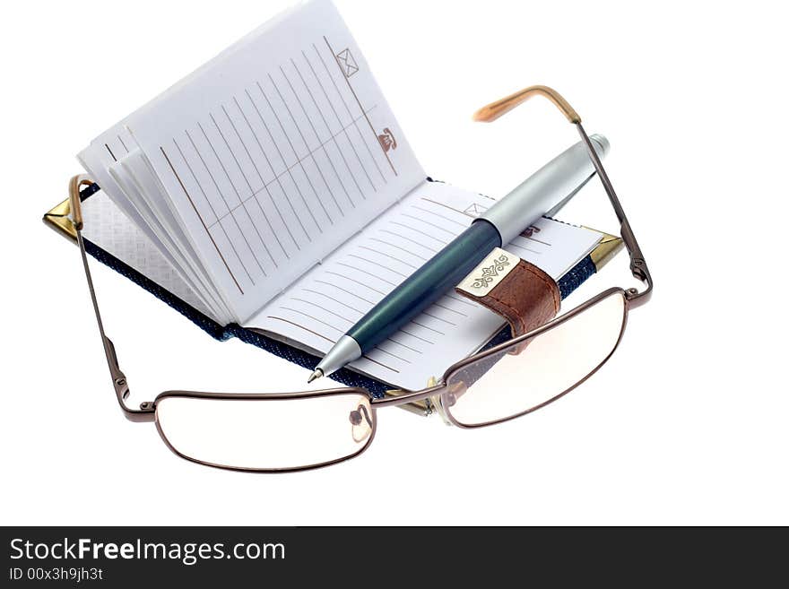 The opened notebook, ball pen and glasses on a white background. The opened notebook, ball pen and glasses on a white background