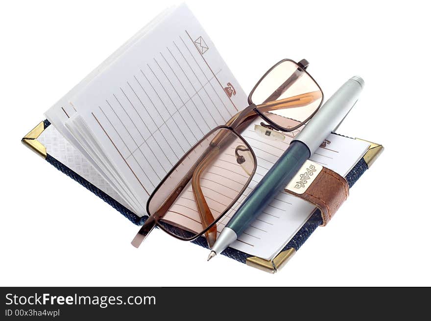 The opened notebook, ball pen and glasses on a white background. The opened notebook, ball pen and glasses on a white background