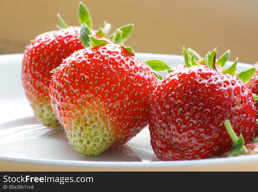 Three delicious strawberries on a white plate