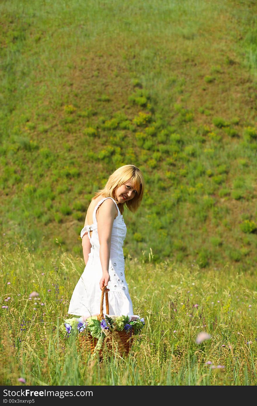 Sexy girl walk away with basket on a meadow