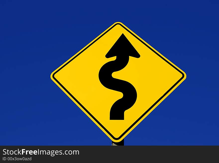 Yellow street sign with curves against blue sky. Yellow street sign with curves against blue sky