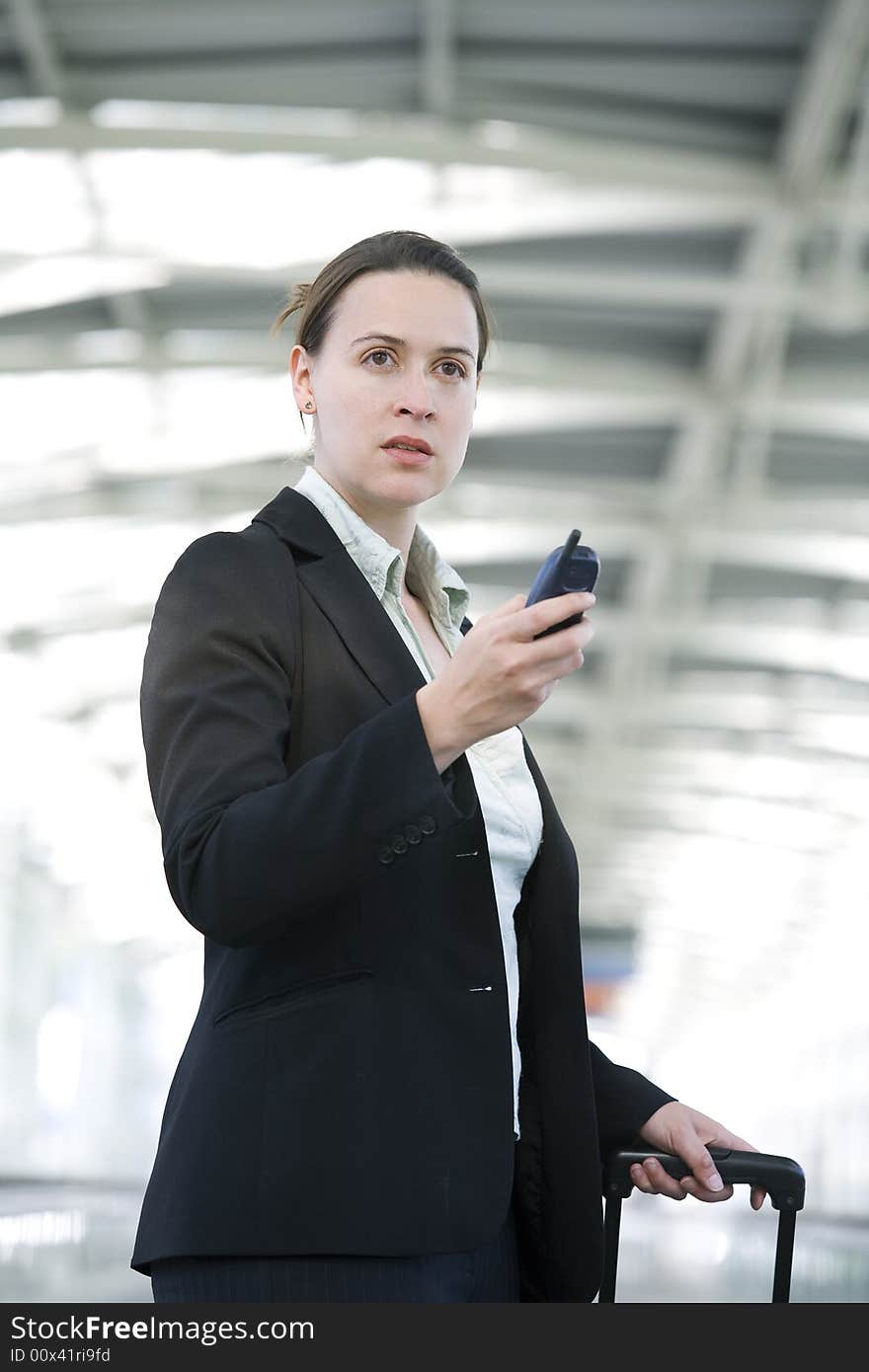 A business woman in an airport setting with a cellular phone. A business woman in an airport setting with a cellular phone