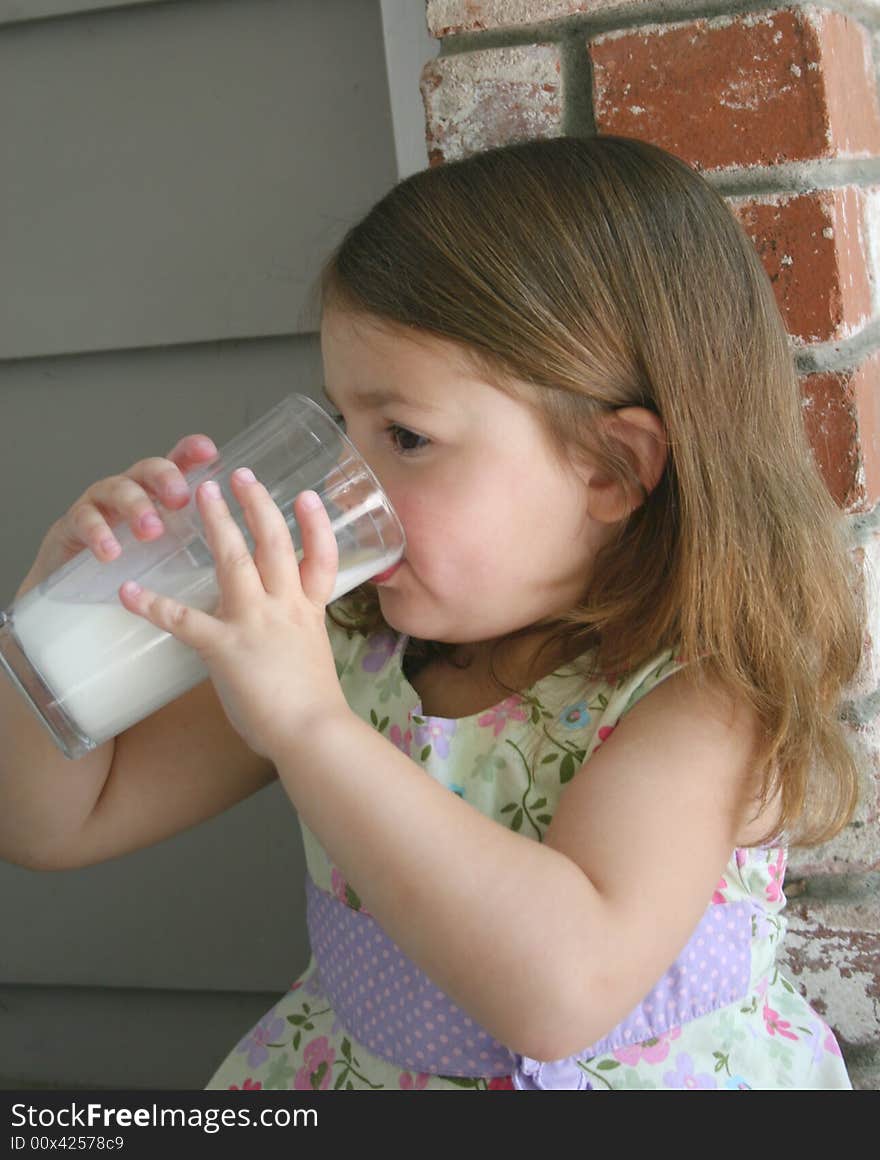 A healthy little girl drinking a fresh glass of cold milk. A healthy little girl drinking a fresh glass of cold milk