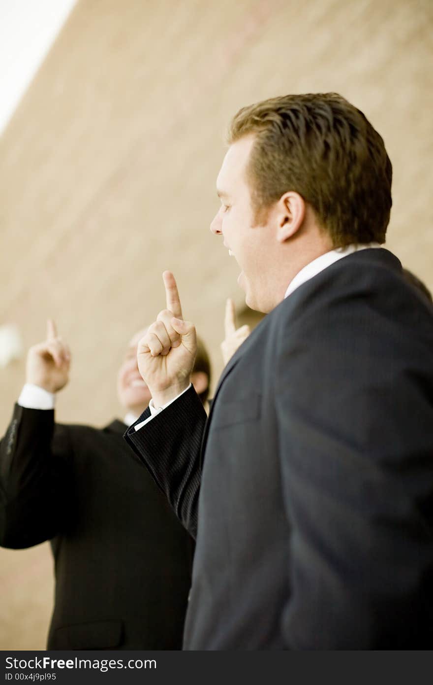 Businesspeople standing together with hands pointing upward and smiling. Businesspeople standing together with hands pointing upward and smiling