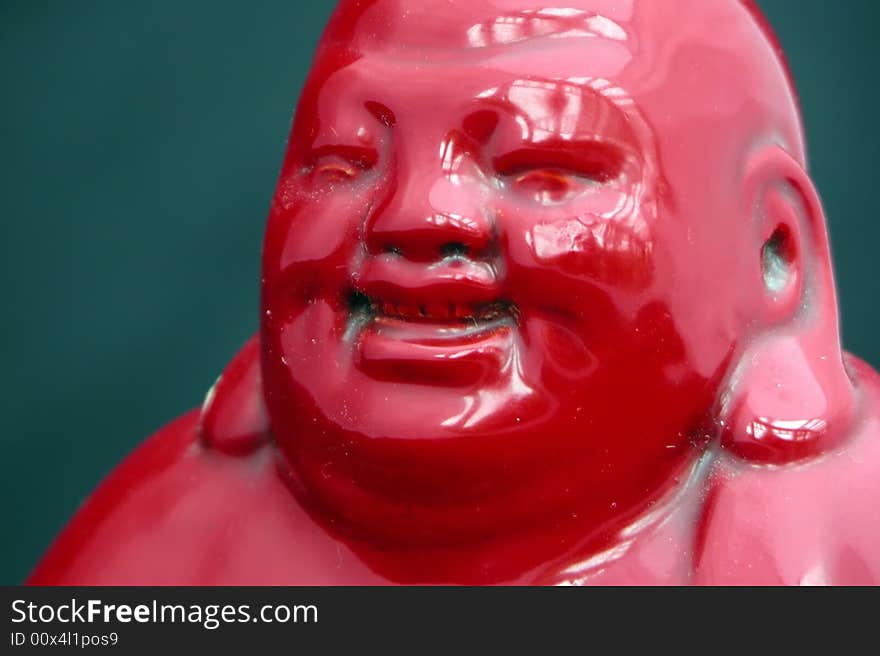 A shiny red Laughing Buddha isolated on dark green. A shiny red Laughing Buddha isolated on dark green