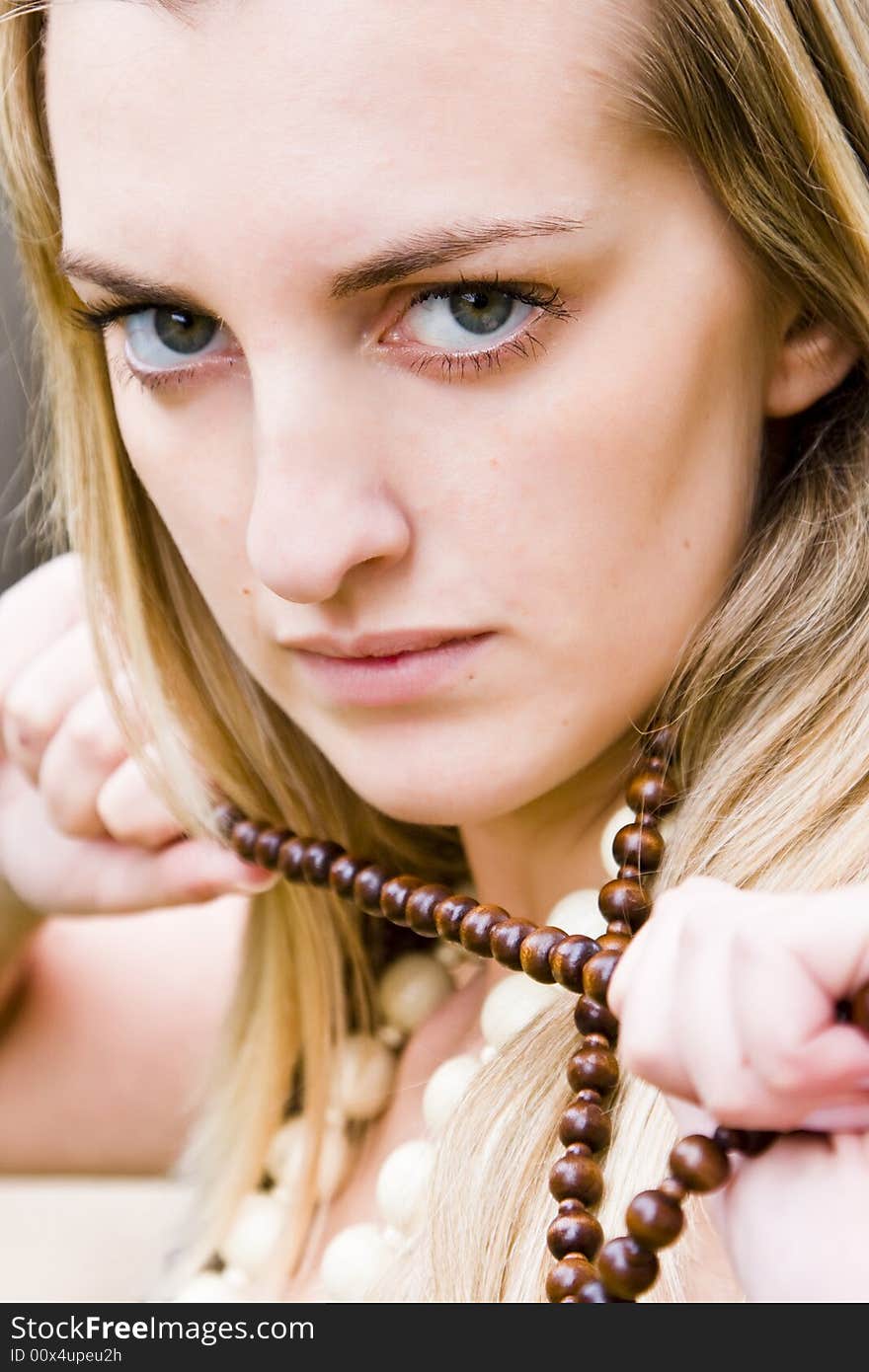 Young blond woman holding a necklace. Young blond woman holding a necklace.