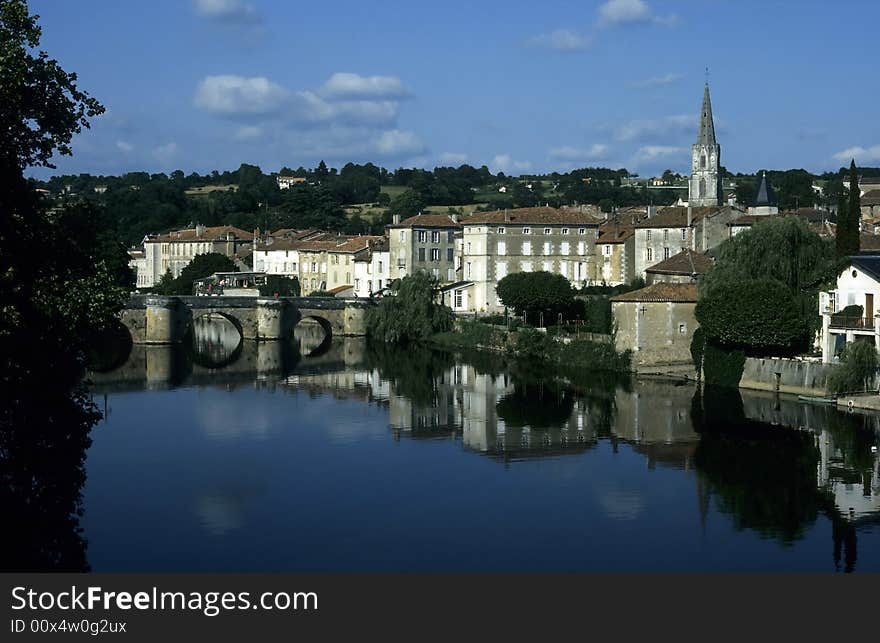 Old french town reflected in a still river crossed by a stone arched bridge. Old french town reflected in a still river crossed by a stone arched bridge