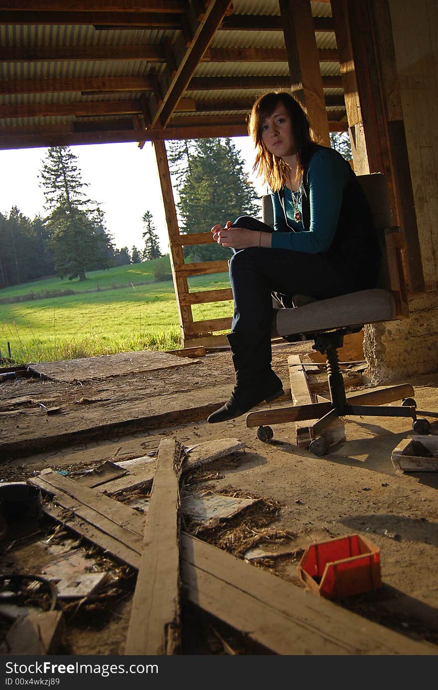 Girl sitting on a chair in an abundant barn. Girl sitting on a chair in an abundant barn