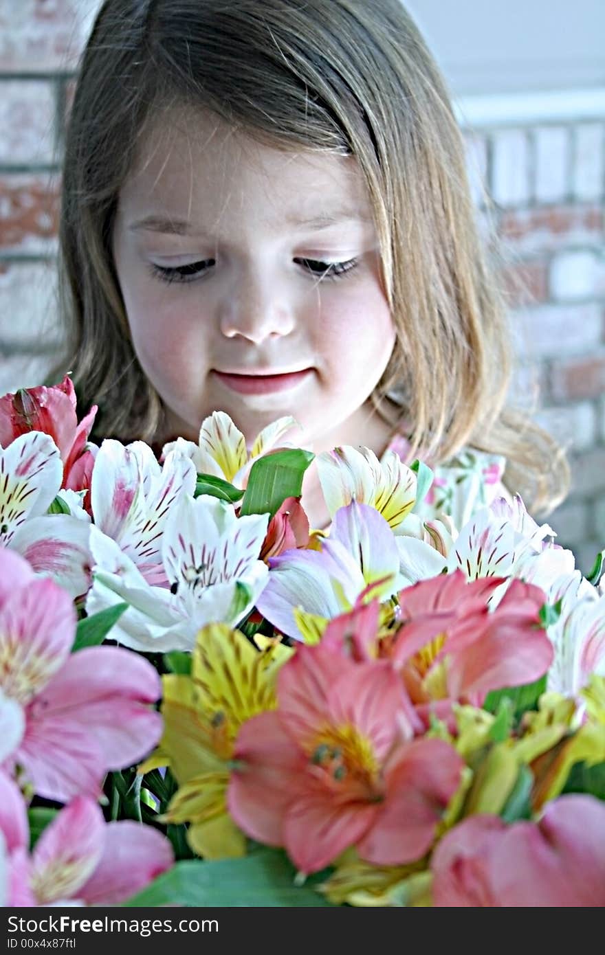 A little girl looks thoughtfully into a bunch of fresh cut flowers. A little girl looks thoughtfully into a bunch of fresh cut flowers