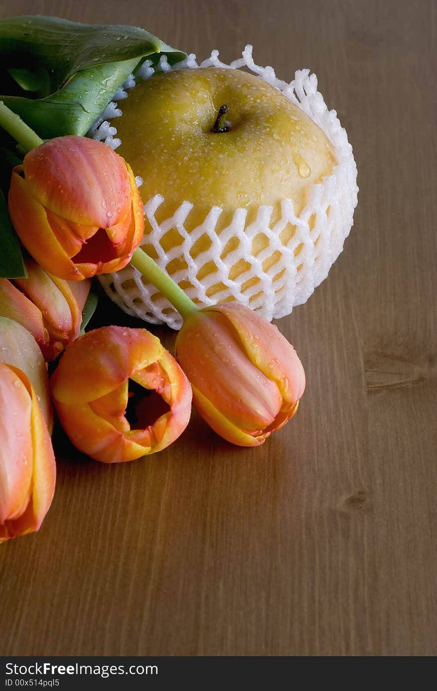 Asian (Nashi) Pear on wood table with orange tulips. Natural light.