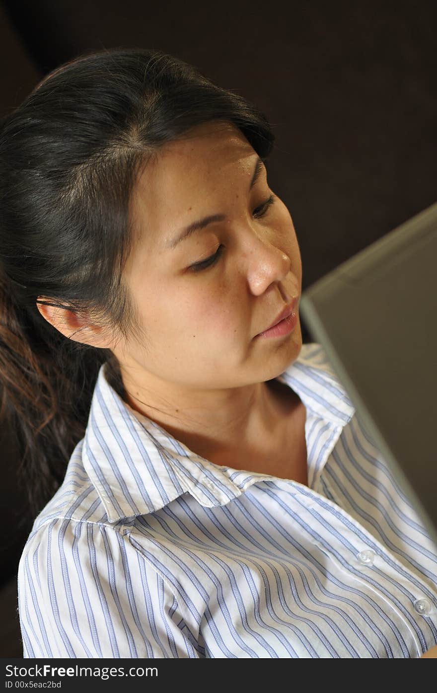 An asian lady using a laptop to do her work. An asian lady using a laptop to do her work