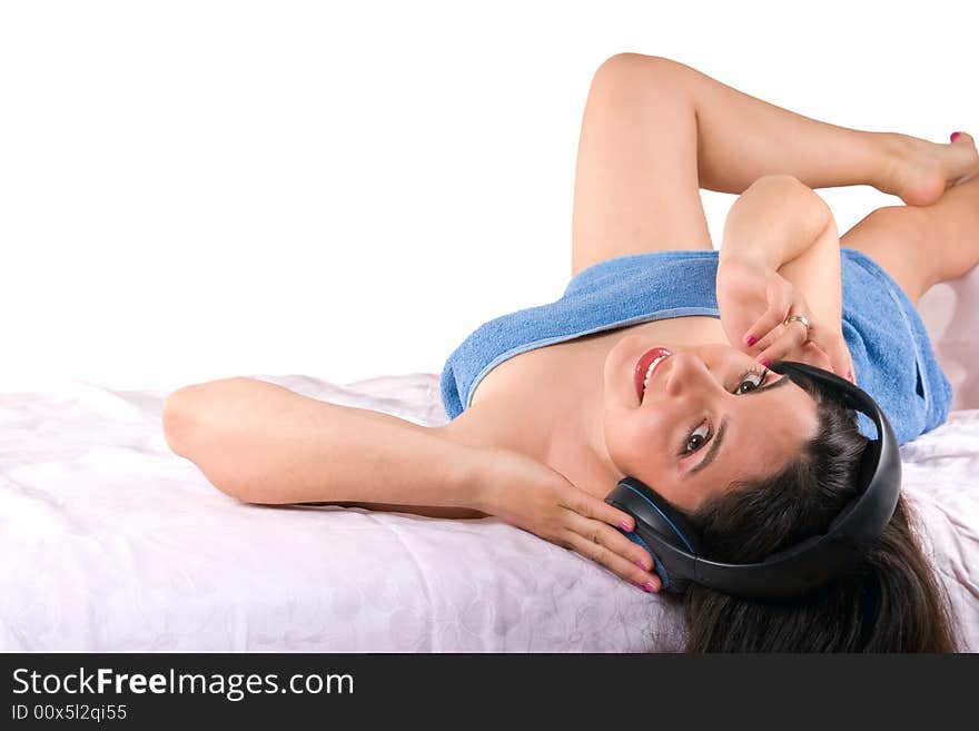 A beautiful girl, lying wrapped in a blue towel, wearing headphones, enjoying the music. A beautiful girl, lying wrapped in a blue towel, wearing headphones, enjoying the music