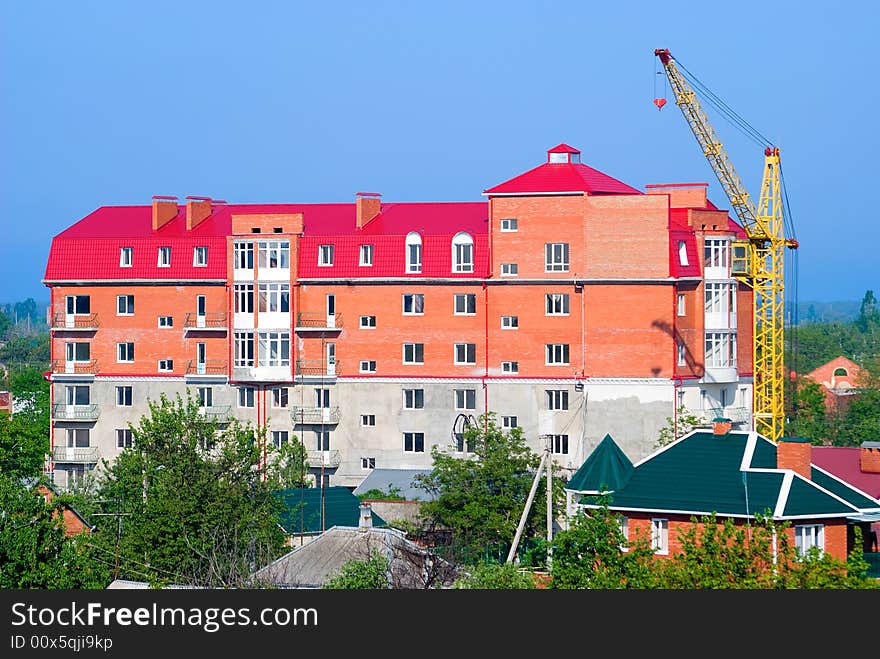 The building crane stands near a abuilding house. The building crane stands near a abuilding house