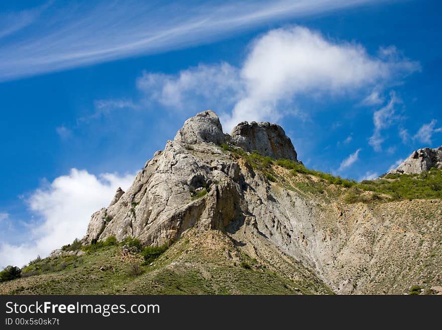 Blue sky with clouds over big rock