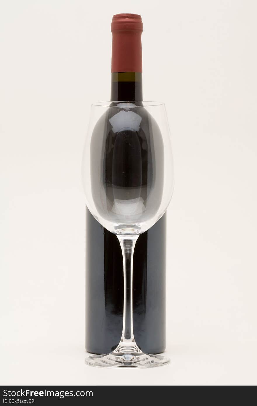 Red wine bottle with empty glass in front